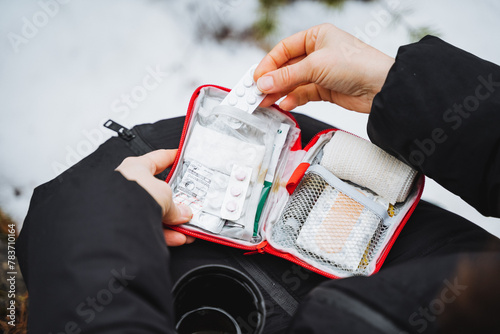 A first-aid kit in the hands of a woman lies open on her knees, a girl takes pills from the first aid kit, a small hiking bag with medicines. photo
