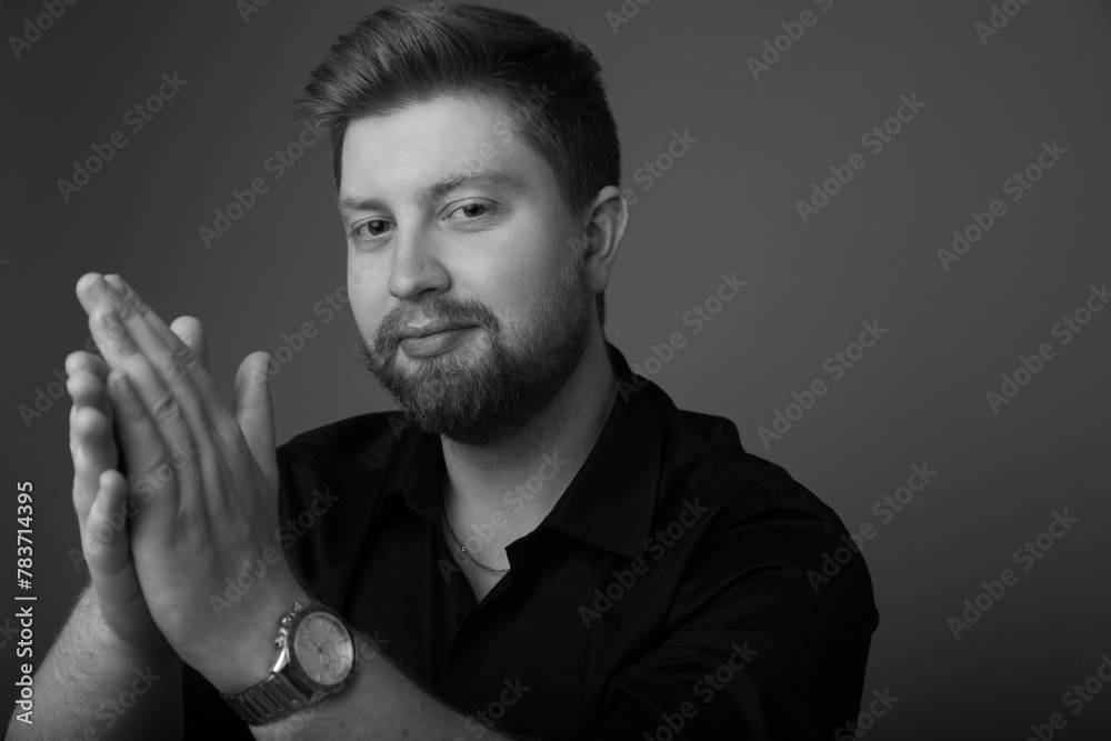 Black and white studio portrait of a caucasian male in his 20s wearing a black button up and watch. He is handsome with light hair and a beard. There is copy space. Black and white studio portrait of a caucasian male in his 20s wearing a black button up and watch. He is handsome with light hair and a beard. There is copy space.