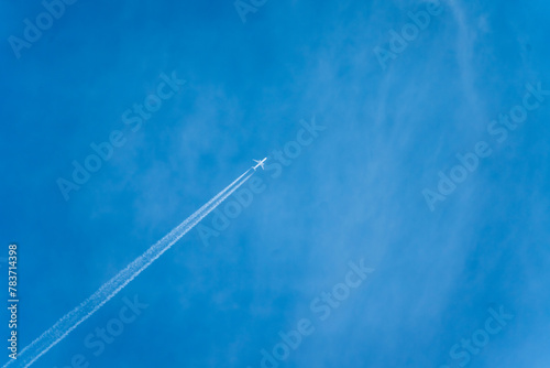 飛行機雲を引きながら青空を飛行するジェット機