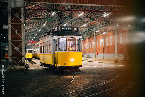 Iconic vintage yellow tram 15 resting in a Lisbon garage at night, symbolizing the city's charm and tourist allure.