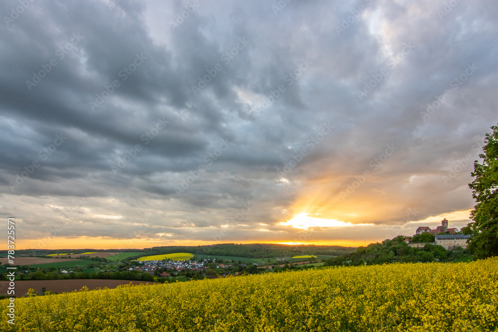 Landscape at sunrise. Beautiful morning landscape with fresh yellow rapeseed fields in spring. Small castle in the yellow fields on a hill. Historic Ronneburg Castle, Ronneburg, Hesse, Germany