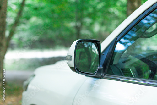 Car in nature, body part front view, driver's mirror close-up. Car side mirror represents reflection, awareness, safety, and the visual extension of the driver's field of view