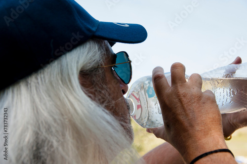 Senior thirsty man feel thirst and drinking water from sport bottle for healthy hydration balance. Drink water in summer heat
