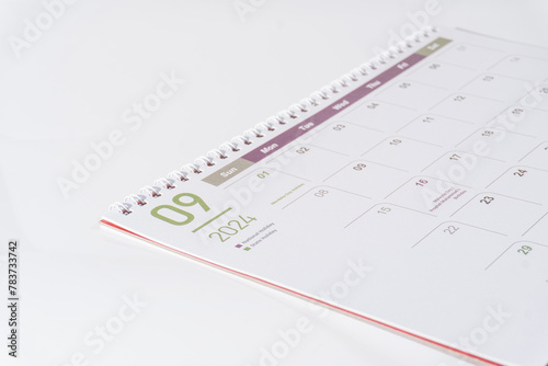 A desk calendar of 2024, September page lying on white background, side view and selective focus shot. Concept of season, time and event in a year. 