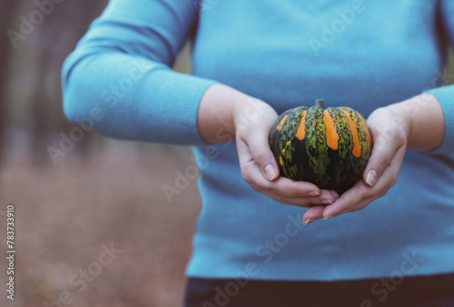 Woman holding orange and green pumpkin