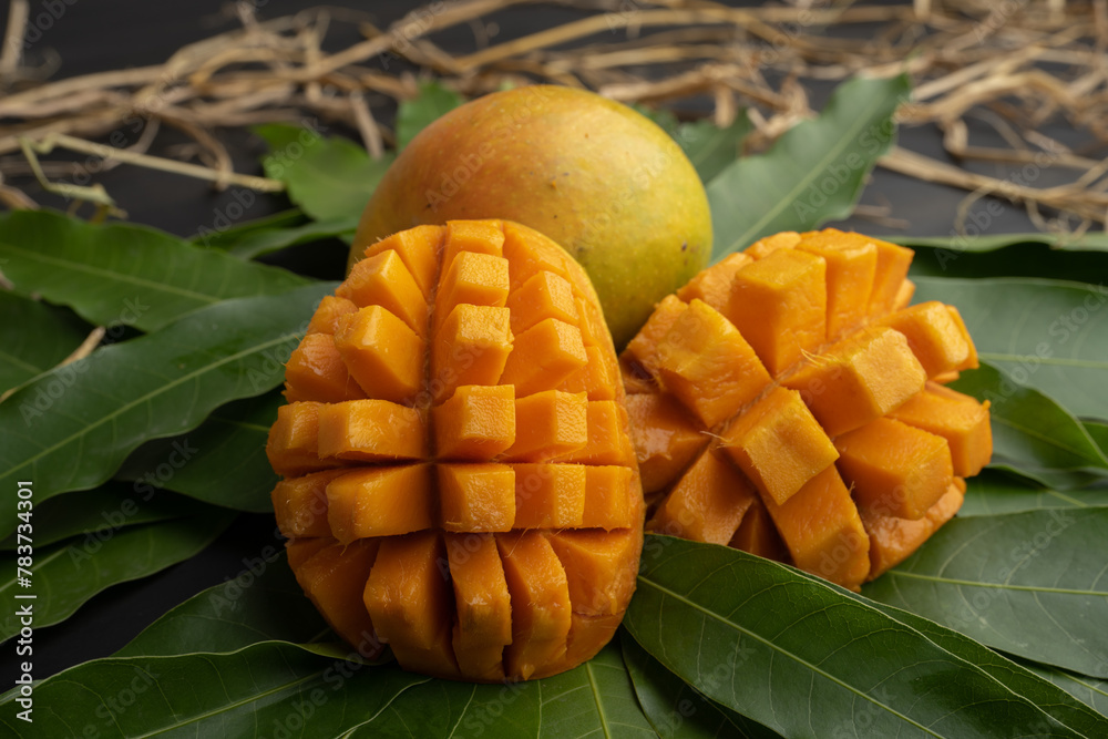 Mango tropical fruit with slice and half cut on green leaf background Mango tropical fruit with slice and half cut on green leaf background