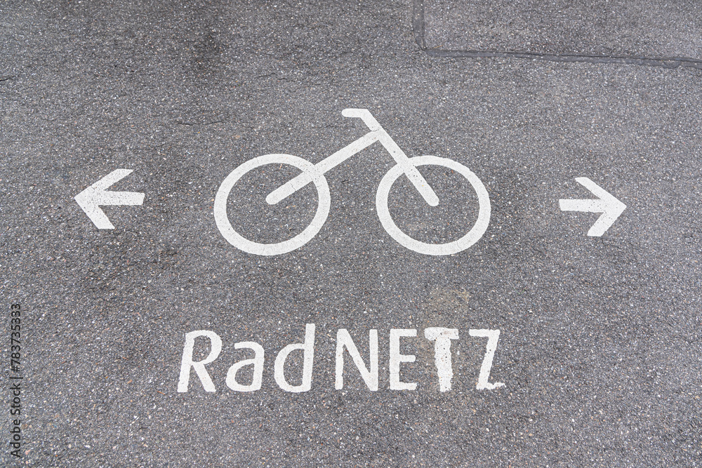 sign on the street with painted bicycle and arrow to left and right and word Radnetz in German sign on the street with painted bicycle and arrow to left and right and word Radnetz in German