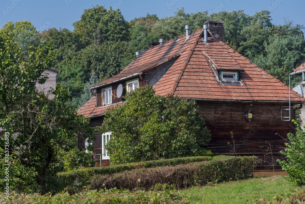Dom „fiński”, zabytkowy drewniany dom wśród drzew. Stary dom wielorodzinny w mieście przy ulicy bogatej w liczne stare drzewa. Dom z dachem pokrytym dachówką ceramiczną. Dom „fiński”, zabytkowy drewniany dom wśród drzew. Stary dom wielorodzinny w mieście przy ulicy bogatej w liczne stare drzewa. Dom z dachem pokrytym dachówką ceramiczną.