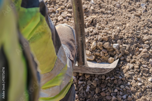 Łopata „operator” - kopanie żwiru na placu budowy. Kopanie żwiru w celu wyrównania poziomu kruszonego kamienia wylanego na fundament. © Grzegorz