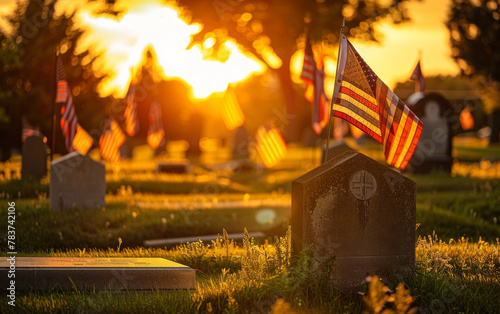 American flags flutter amidst the warm glow of sunset, casting a reverent atmosphere over the gravestones and flowers adorning a military cemetery.