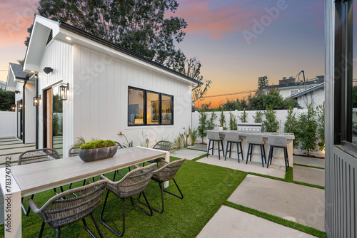 a dining area with tables and chairs on grass lawn in front of house photo