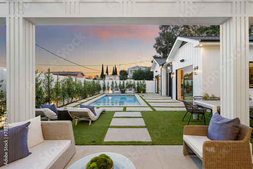 Canvastavla an outdoor lounge area with a pool at sunset on the left and chairs and tables