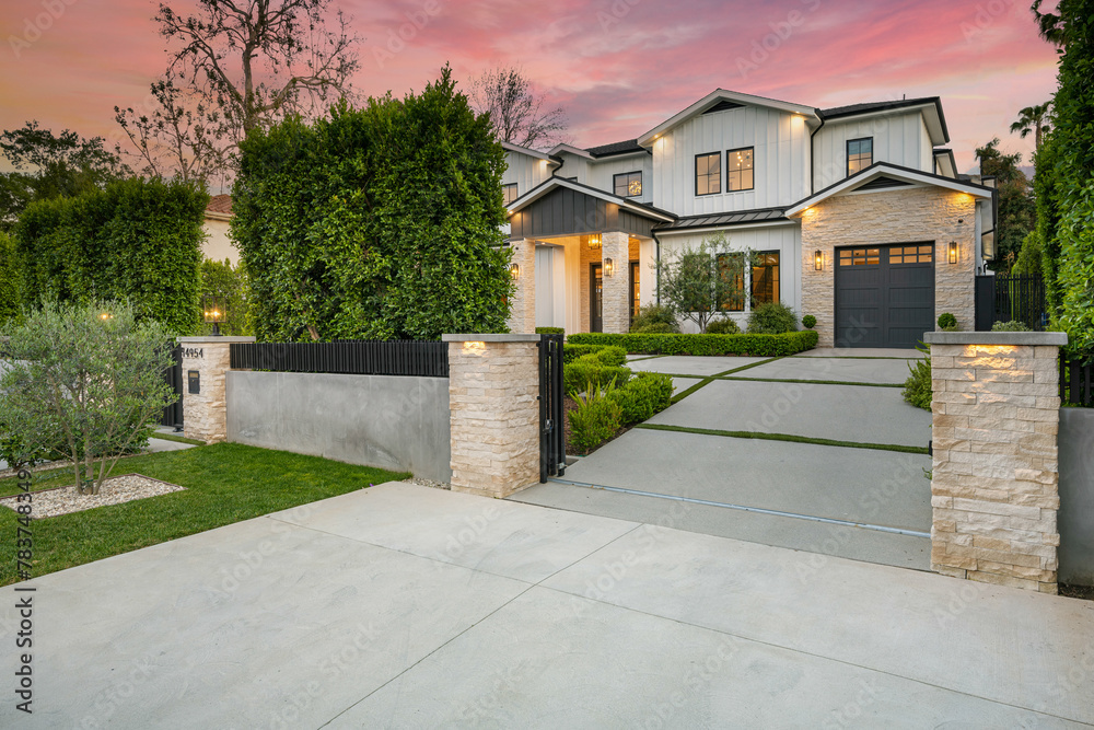 White luxury house with a stone facade and driveway.