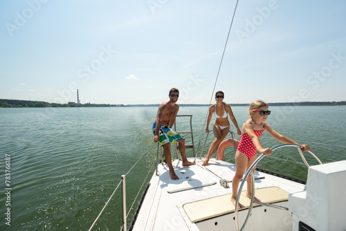  family on a yacht, a girl holding on to the ropes of a yacht, a girl holding the helm of a yacht, girl on a ship, boys in swimsuits, father, family, family of 3 © simonovstas
