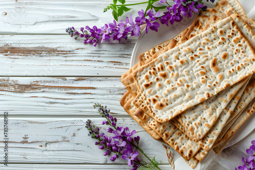 Matzah and spring flowers on light wooden background. Jewish holiday bread matza or matzoh. Happy Passover, Pesah celebration. Flat lay, top view with copy space