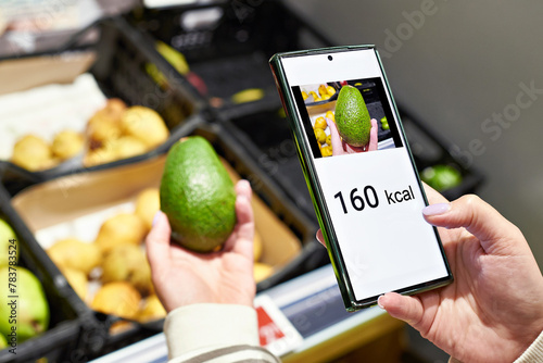 Checking calories on a avocado fruit in store with smartphone