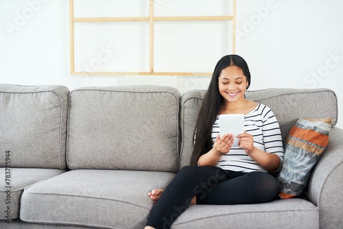 Child, tablet and sofa at home with elearning, online education and upskill app game. Living room, tech and digital reading with social media or youth development learning in a house with smile