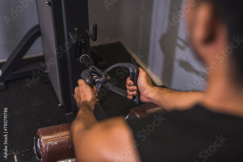 An Asian man performs a set of seated cable rows with v-bar grip in the gym. An intense back workout.