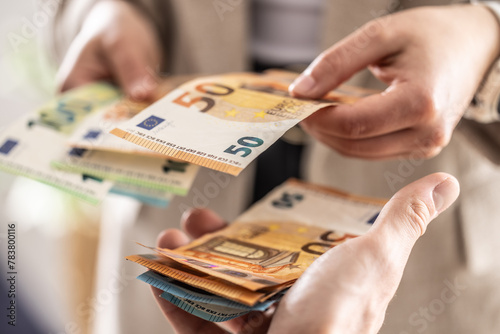 Businesswoman's hands exchanging euro banknotes, closeup shot