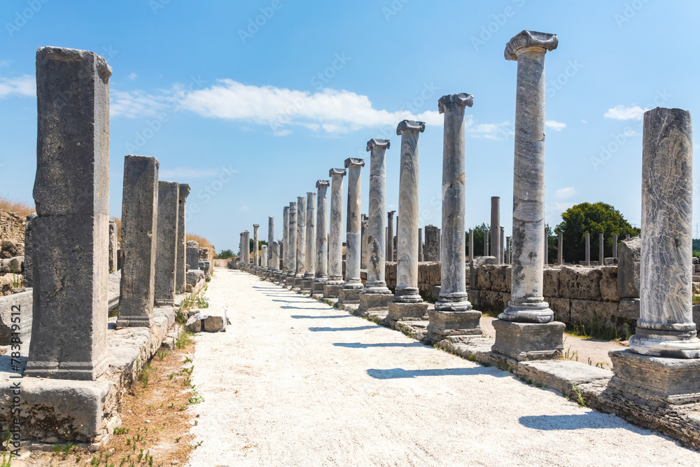 Row of ancient columns on a street in Perge archeological site, under bright blue skies. Antalya, Turkiye (Turkey)