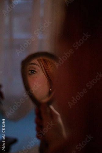 girl watching her eyes in a small mirror photo