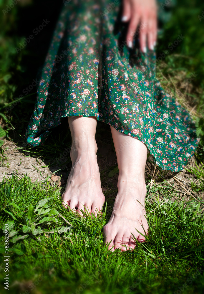 Barefoot woman in a green dress sitting on the grass