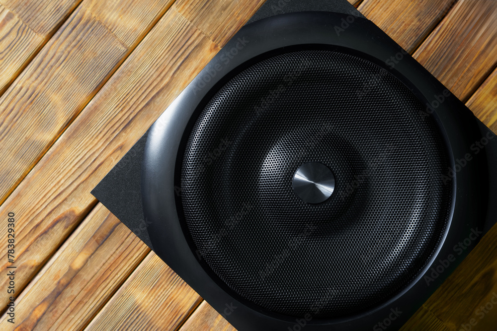 Large cubic subwoofer in a wooden enclosure with metal grille on a background of natural pine boards. Audiophile concept. Natural style Large cubic subwoofer in a wooden enclosure with metal grille on a background of natural pine boards. Audiophile concept. Natural style