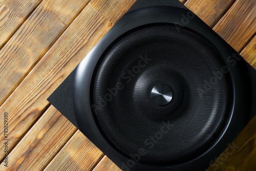 Large cubic subwoofer in a wooden enclosure with metal grille on a background of natural pine boards. Audiophile concept. Natural style