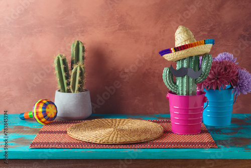 Empty wooden table with place mat  and cactus decoration over wall  background. Mexican party mock up for design and product display