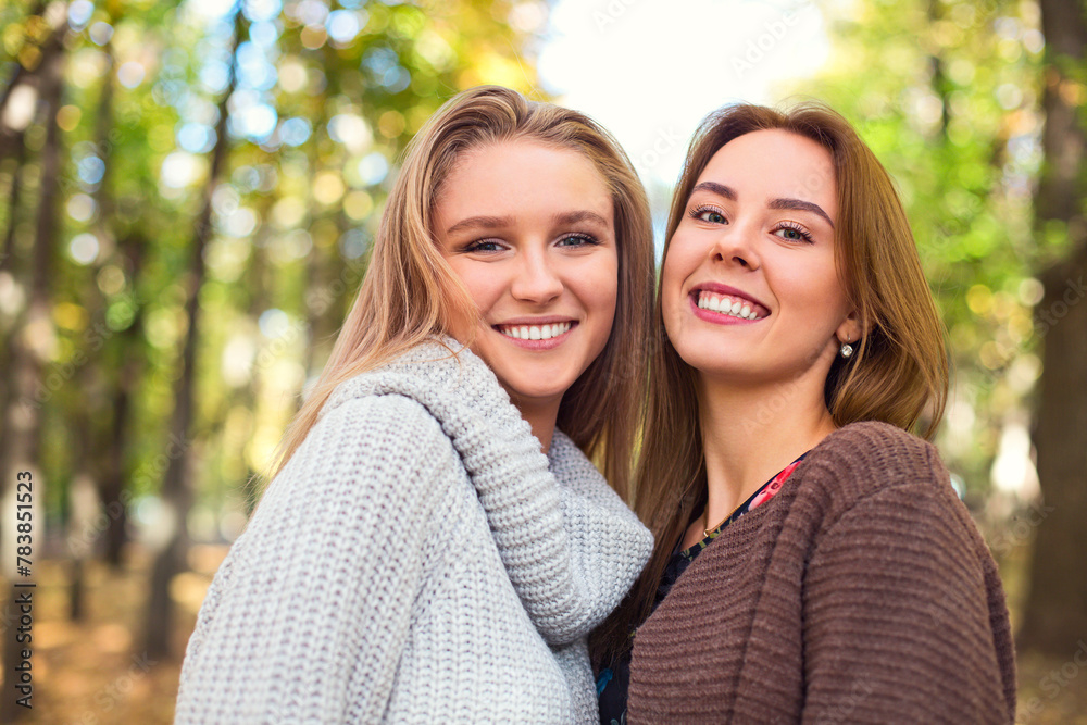 Obraz premium Fashionable beautiful young girlfriends walking together in the autumn park background. Having fun and posing.