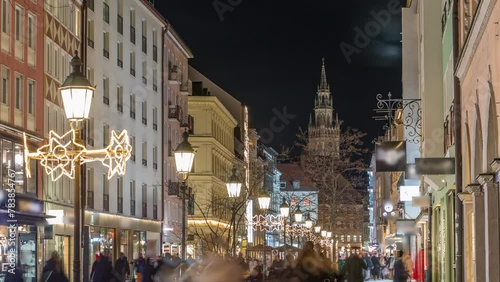 Historic buildings illuminated at the old town of Munich - sendlinger strasse night timelapse. Walking street with benches and streetlights. Glockenspiel on a background. Germany photo