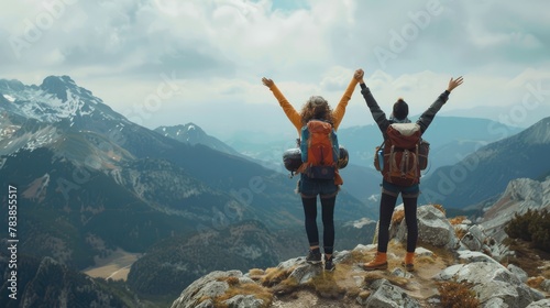 Concept of two mountain climbers raising their arms on the top of the mountain.