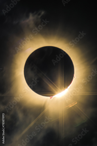 Total solar eclipse of April 8th 2024 with the sun peaking from behind the moon creating. a diamond ring effect. Red prominences and bright corona during totality