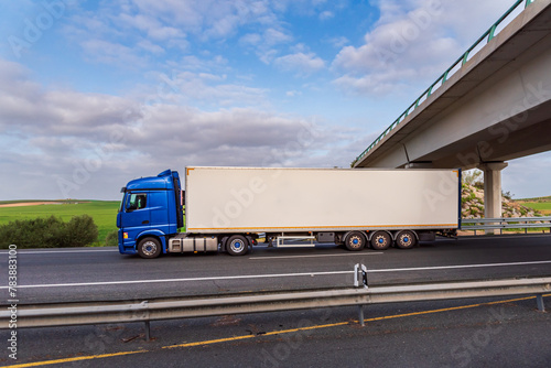Truck driving on a highway at the time of crossing under a bridge, side view.