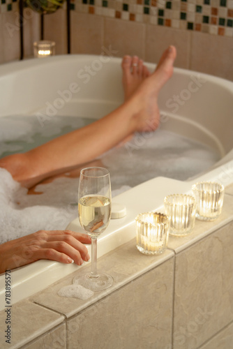 Woman Relaxing in the Bathroom Spa Tub with a Glass of Sparkling Champagne and Candles.