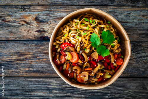 Takeaway food - Asian style stir fried vegetables and noodles on wooden table
