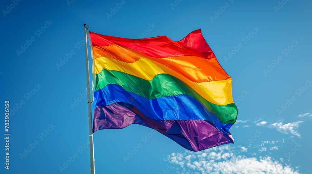 Rainbow of Pride. vibrant pride flag, a symbol of the diverse LGBTQ+ community, is waving against a striking blue sky backdrop. Rainbow of Pride. vibrant pride flag, a symbol of the diverse LGBTQ+ community, is waving against a striking blue sky backdrop.