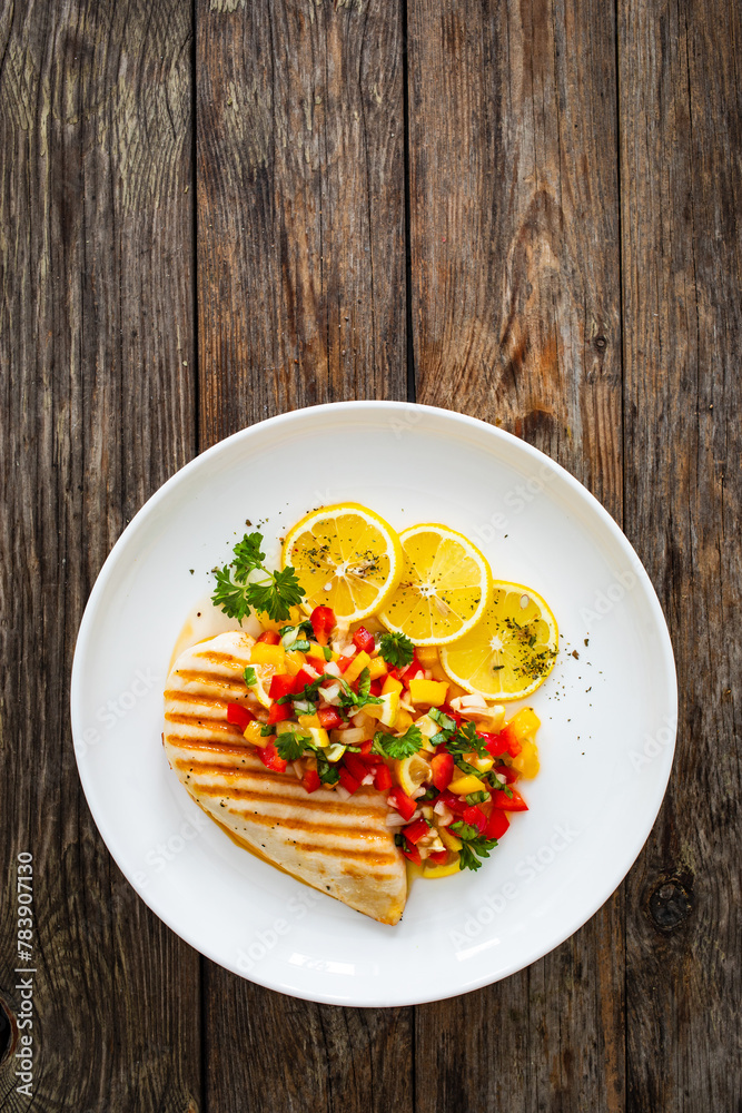 Grilled chicken breast and fresh vegetables on wooden table
Grilled chicken breast and fresh vegetables on wooden table
