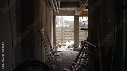 Construction site corridor with electrical fittings, pipes and materials. Unfinished building from inside, works in progress