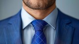   A man in a blue suit and checked blue tie  is depicted in this close-up image