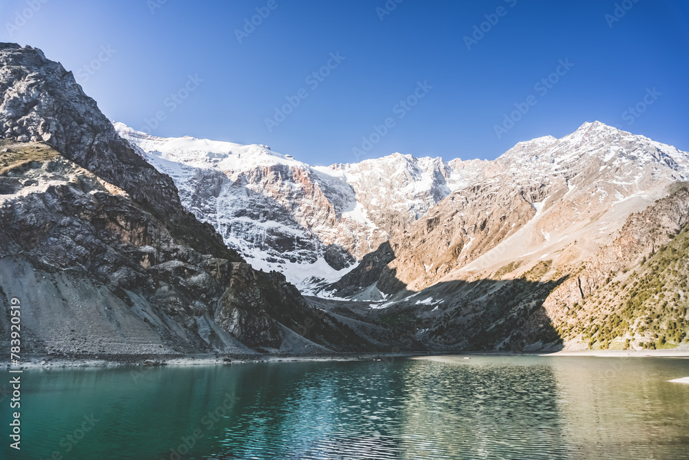 Mountain landscape with Kulikalon lake and rocky peaks with snow and ice, in the Fan Mountains in Tajikistan in the morning
