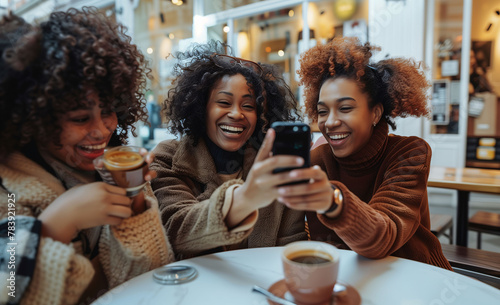 A group of friends of different ethnicities have fun, joke and take a selfie, while having a coffee in a cafe. Moments between friends, complicity and camaraderie.