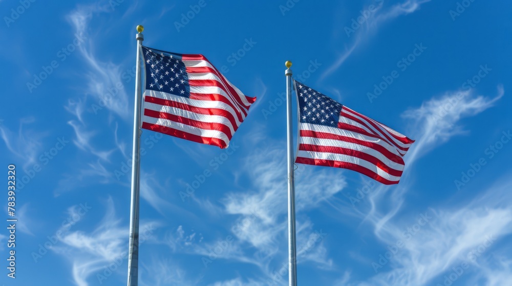 Two American flags waving against blue sky. National pride and freedom concept.