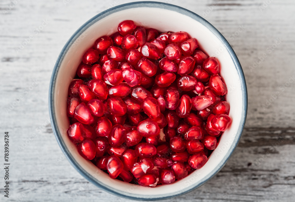 Juicy organic pomegranate seeds in a bowl, centered. Juicy organic pomegranate seeds in a bowl, centered.