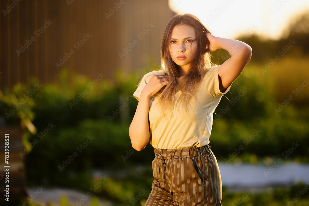 Photo shoot in countryside during golden hour, young European woman posing for photographer outdoors.