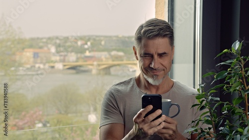 Man drinking morning coffee using phone at home © nyul