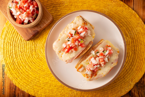 Molletes. Mexican recipe based on bolillo bread split lengthwise, spread with refried beans and gratin cheese, adding pico de gallo sauce and some protein such as ham, bacon or chorizo. photo