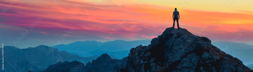 Lone mans silhouette atop a mountain, sunset behind, vibrant colors, telephoto view