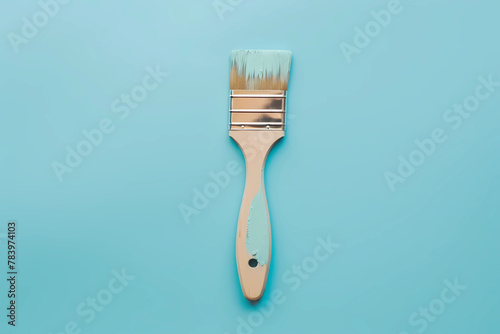 A wide paint brush its bristles saturated with a soothing shade of light blue, poised against a background of the same serene hue, invites a moment of contemplation, hinting at boundless possibilities