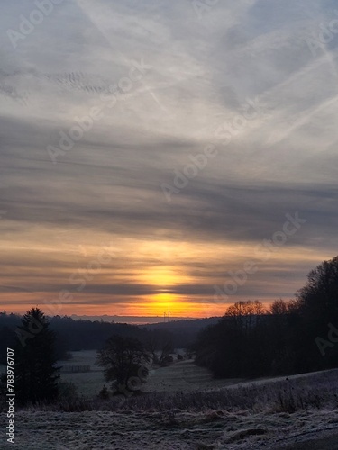 A frosty morning at sunrise and a little fog over meadows and forests